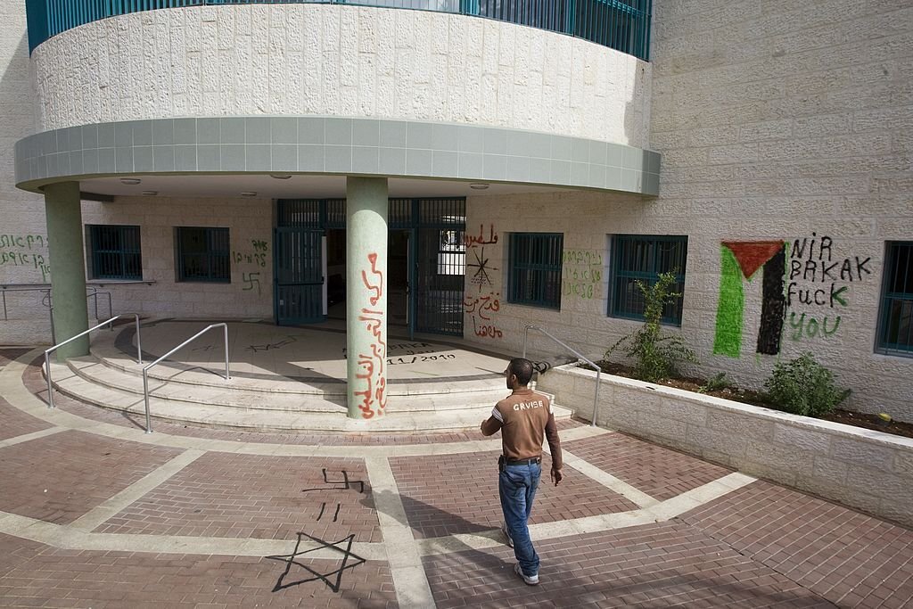 شاب فلسطيني في ساحة إحدى المدارس التابعة لبلدية الاحتلال في القدس، بعد أن خُطّت شعارات وطنية على جدرانها عشية افتتاحها من قبل رئيس البلدية في حينه نير بركات، تشرين الثاني 2010. (أحمد غرابلي/ وكالة الصحافة الفرنسية).