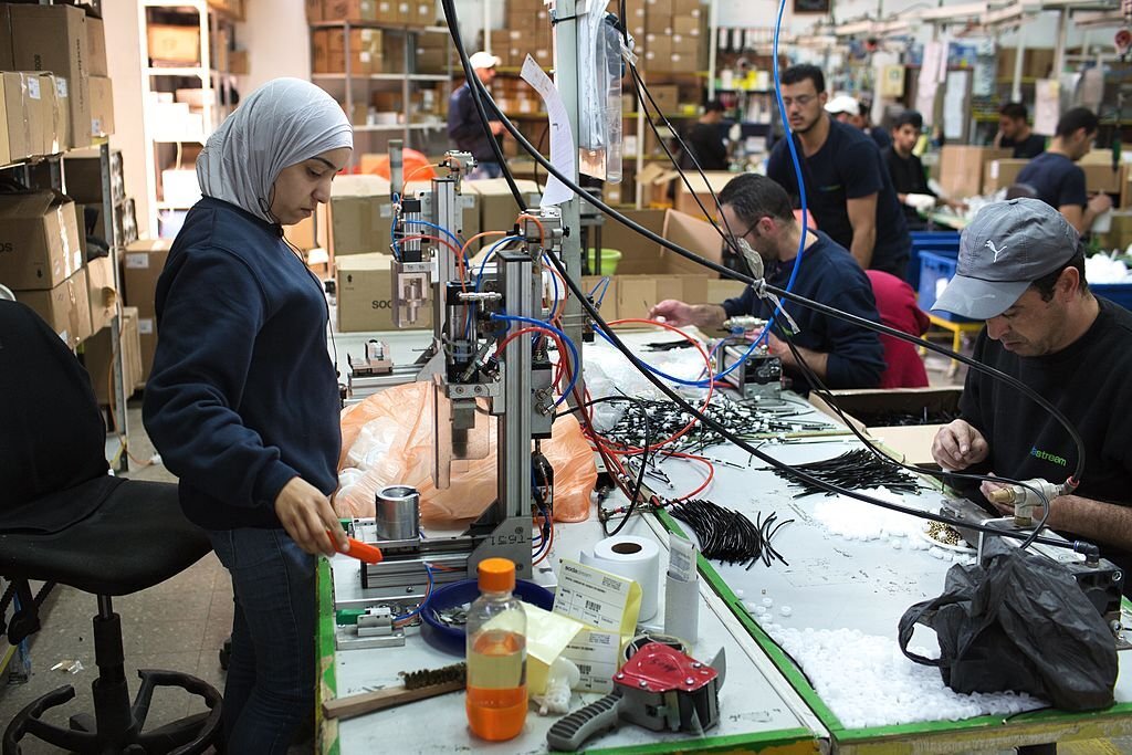 الضفة الغربية، 2014، أحزمة الفقر كعمالة رخيصة لدى الاحتلال. عمّال فلسطينيون يعملون في مصنع "سودا ستريم" الإسرائيلي، في المنطقة الصناعية الاستيطانية ميشور أدوميم، شرق القدس، بالقرب من مستوطنة معاليه أدوميم، (وكالة الصحافة الفرنسية).