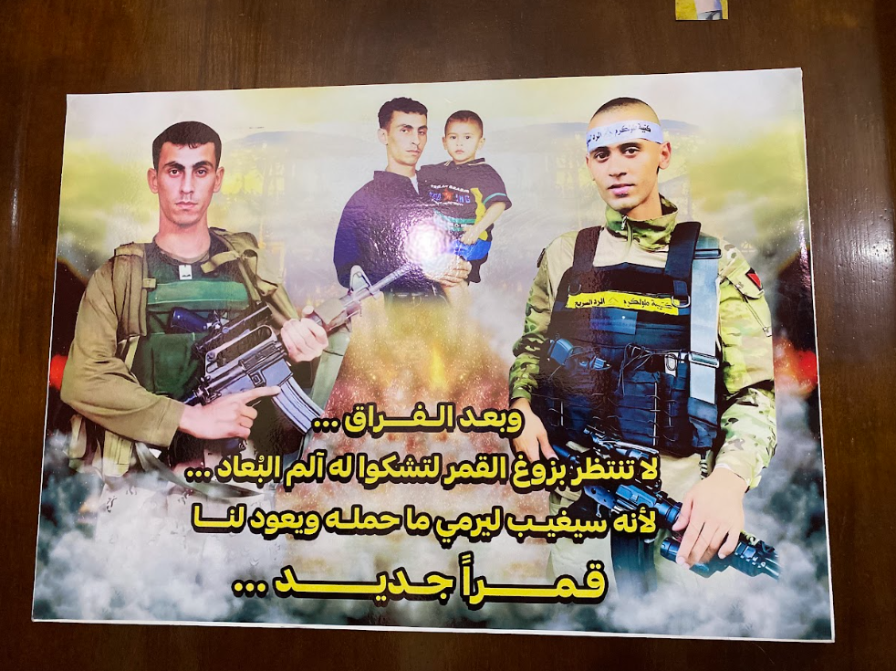 ملصق معلق على باب إحدى غرف منزل الشهيد جهاد شحادة. يظهر فيه الشهيد جهاد والشهيد رائد الكرمي، وصورة قديمة تجمعهما. عدسة: شذى حمّاد.