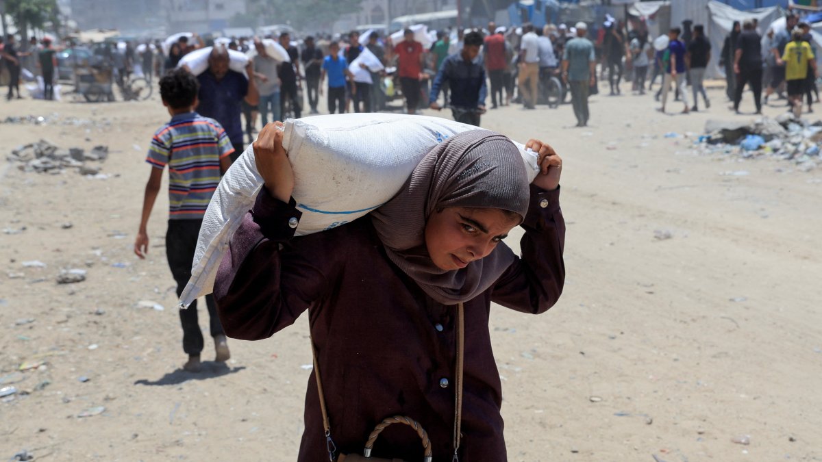 فتاة فلسطينية تحاول حمل كيساً من الطحين بعد الحصول عليه من شاحنات المساعدات في خانيونس جنوب قطاع غزة، 26 حزيران/ يونيو 2025. (المصدر: رويترز)
