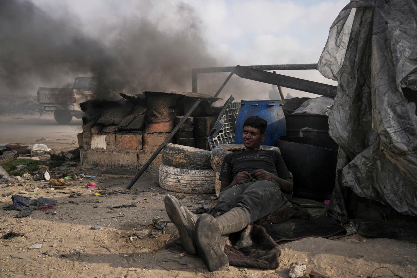 بعد ساعات طويلة من العمل والتعرض للنار والدخان السام الناتج عن عملية صهر البلاستيك، أحد الشبان يأخذ استراحة بالقرب من مكان عمله الذين يعتبر الوسيلة الوحيدة لكسف المال وإعالة أسرته. (تصوير: عبد الكريم حنا/ وكالة أسوشيتد برس) 
