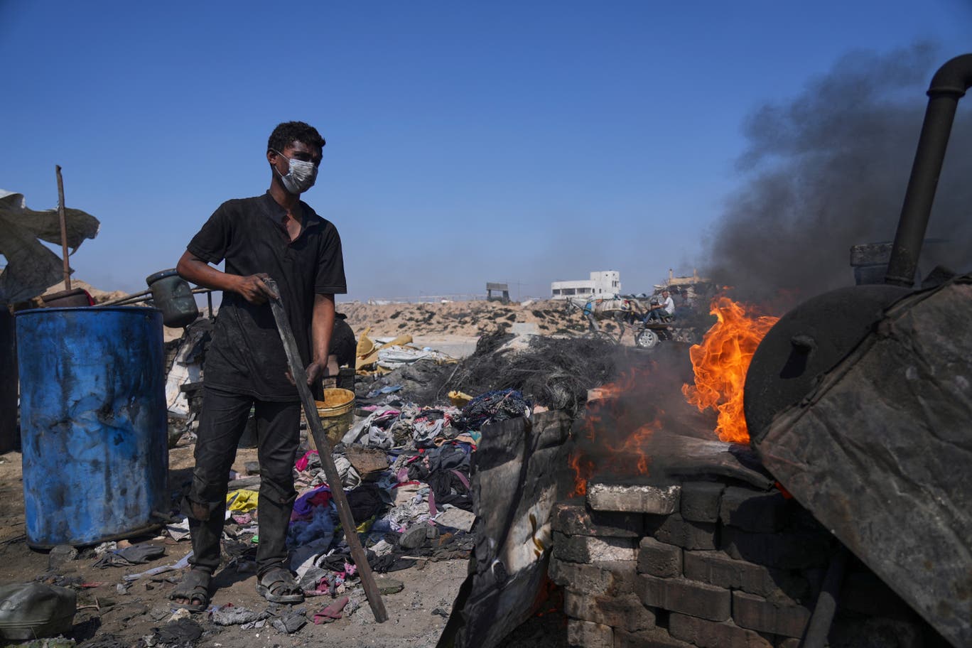 فلسطيني يقوم بحرق البلاستيك في مواقد بدائية الصنع، جنوبي مدينة غزة، بهدف انتاج الوقود، وذلك بعد جمع النفايات البلاستيكية، ثم معالجتها في براميل معدنية، ثم يعبئونه ويبيعونه للمارة.(تصوير: عبد الكريم حنا/ وكالة أسوشيتد برس) 
