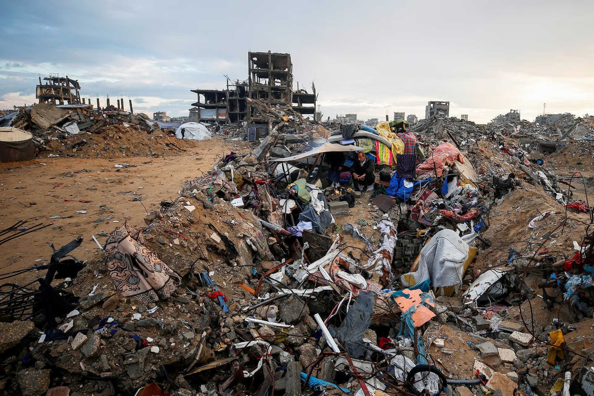 رجل فلسطيني يجلس قرب النار وسط أنقاض منزله في مخيم جباليا شمال قطاع غزة، 11 شباط/ فبراير 2025. (مصدر الصورة: رويترز/محمود عيسى)
